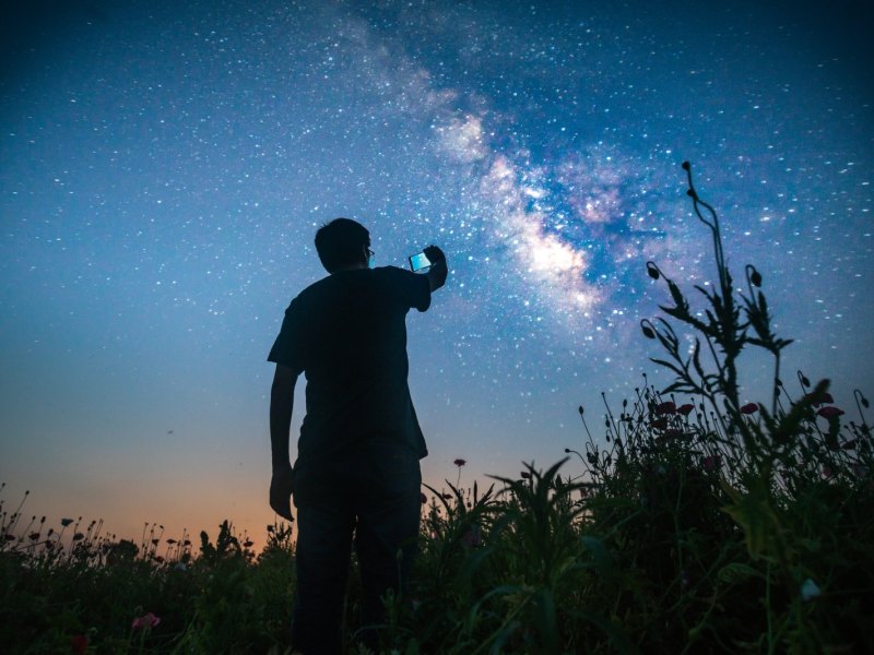 Mann mit Handy fotografiert den Sternenhimmel
