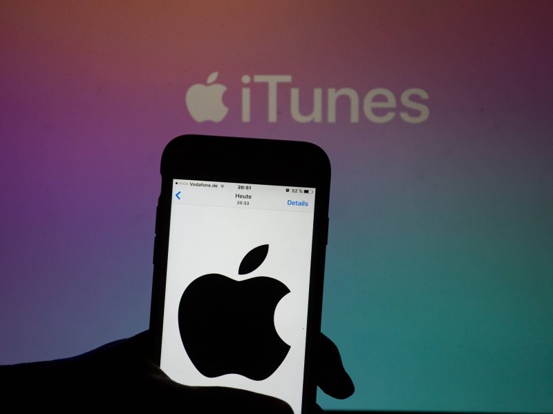 iPhone mit Apple-Logo vor dem iTunes-Logo