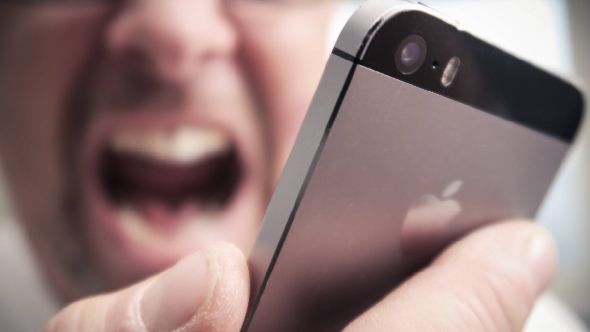 Ein Mann schreit sein iPhone an.