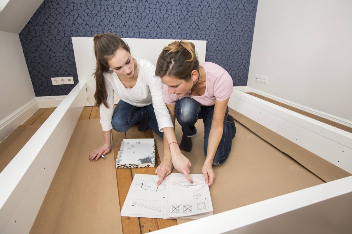 Frauen bauen ein Ikea-Bett zusammen.