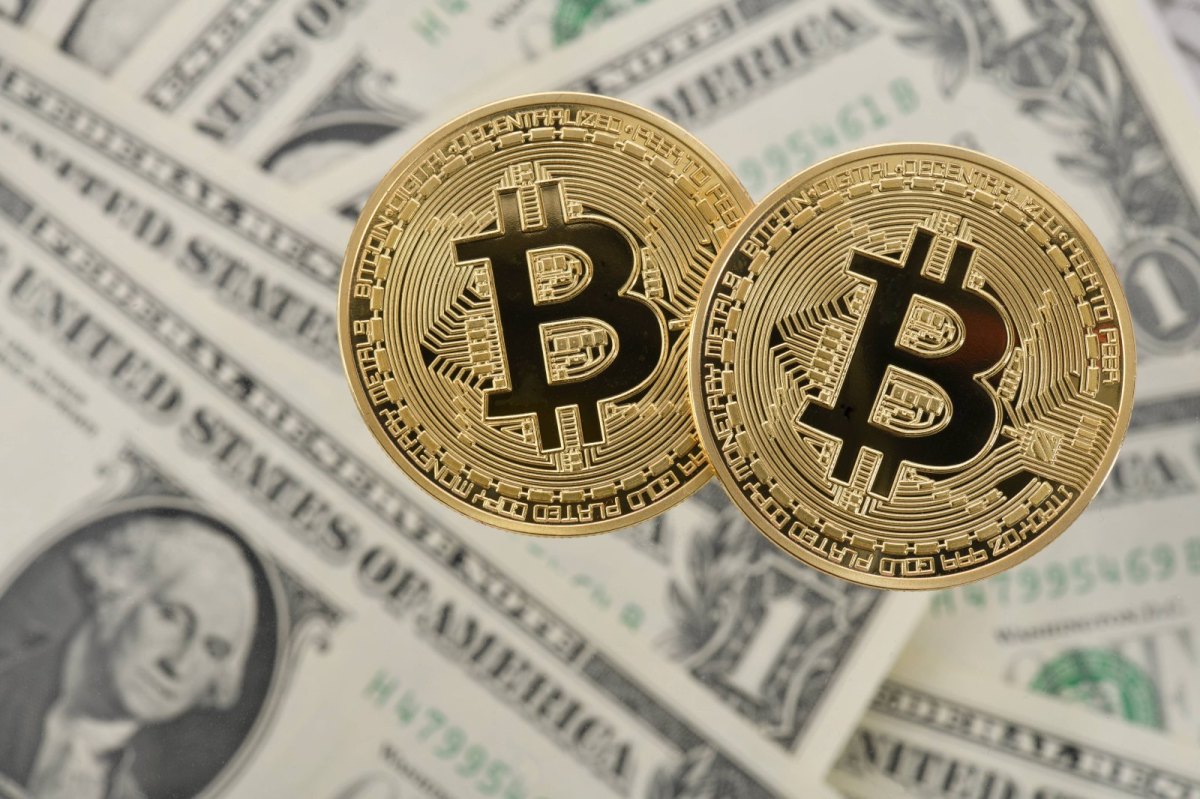 Zwei Bitcoin-Münzen liegen auf amerikanischen Dollar-Noten.