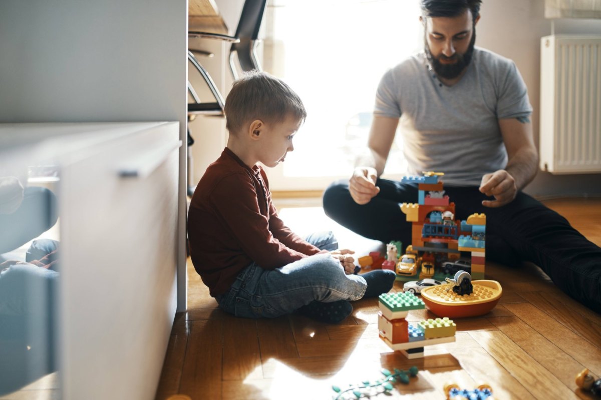 Kind und Erwachsener spielen mit Legosteinen