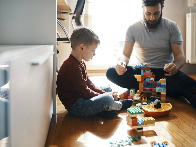 Kind und Erwachsener spielen mit Legosteinen