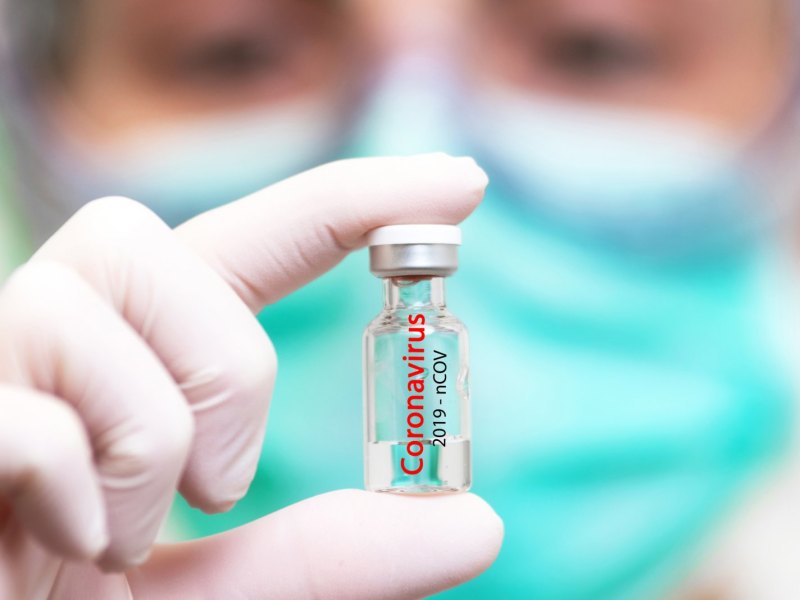 Frau hält Ampulle mit Coronavirus-Impfstoff