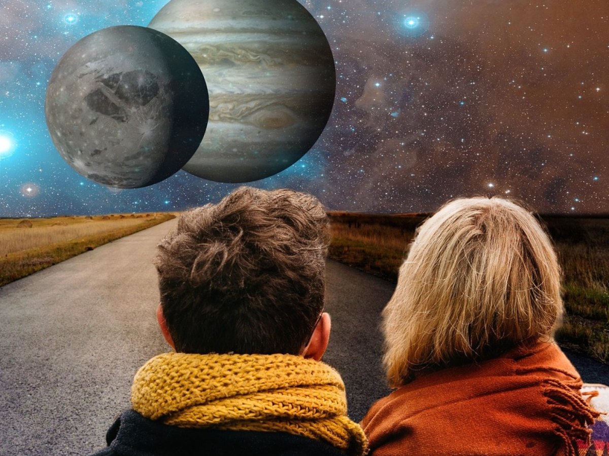 Mann und Frau stehen auf einer Straße und sehen ins All mit zwei Planeten