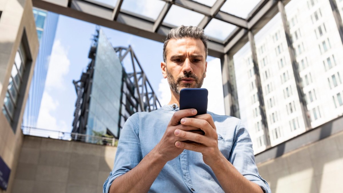 Ein Mann starrt verwundert auf sein Smartphone.