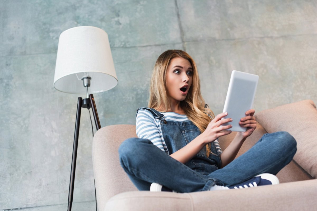 Frau schaut erstaunt auf ein Tablet.