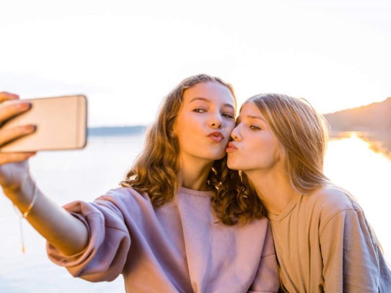 mädchen kussmund am see mit smartphone selfie