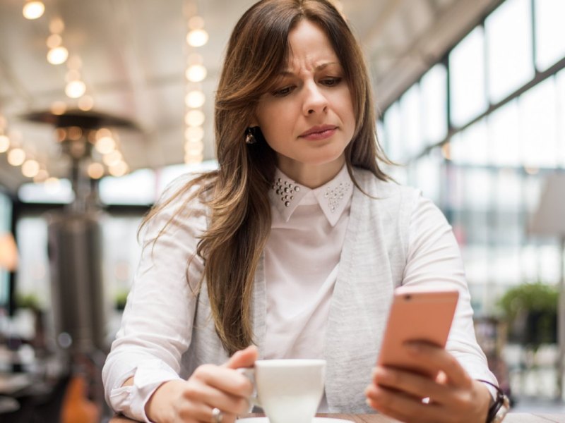 Frau schaut böse auf ihr Handy.