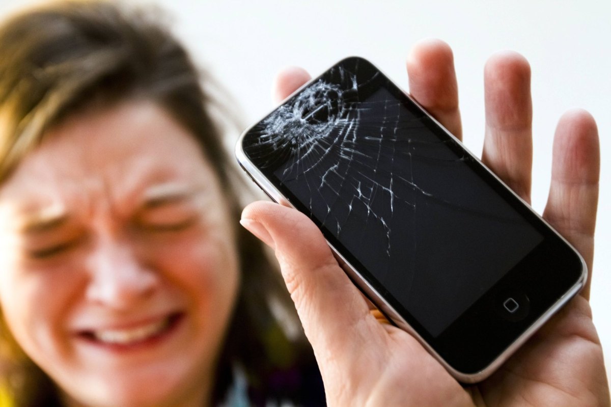 Eine Frau weint und hält ein kaputtes iPhone in der Hand.