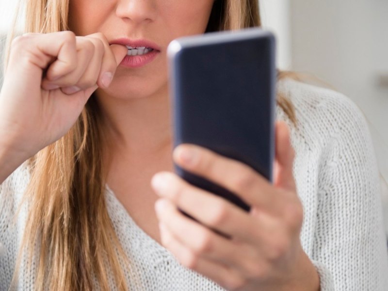 Frau blickt besorgt auf ihr Handy.