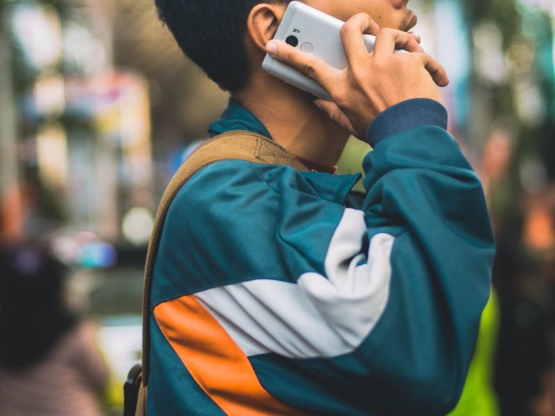 Junger Mann in Trainingsjacke telefoniert mit seinem Android-Smartphone