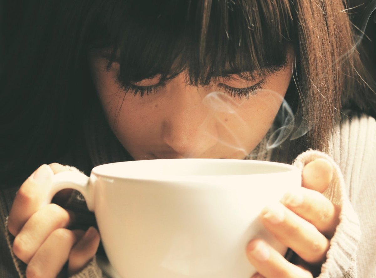 Frau riecht an Tasse mit Kaffee