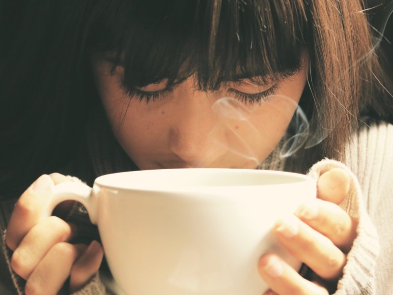 Frau riecht an Tasse mit Kaffee