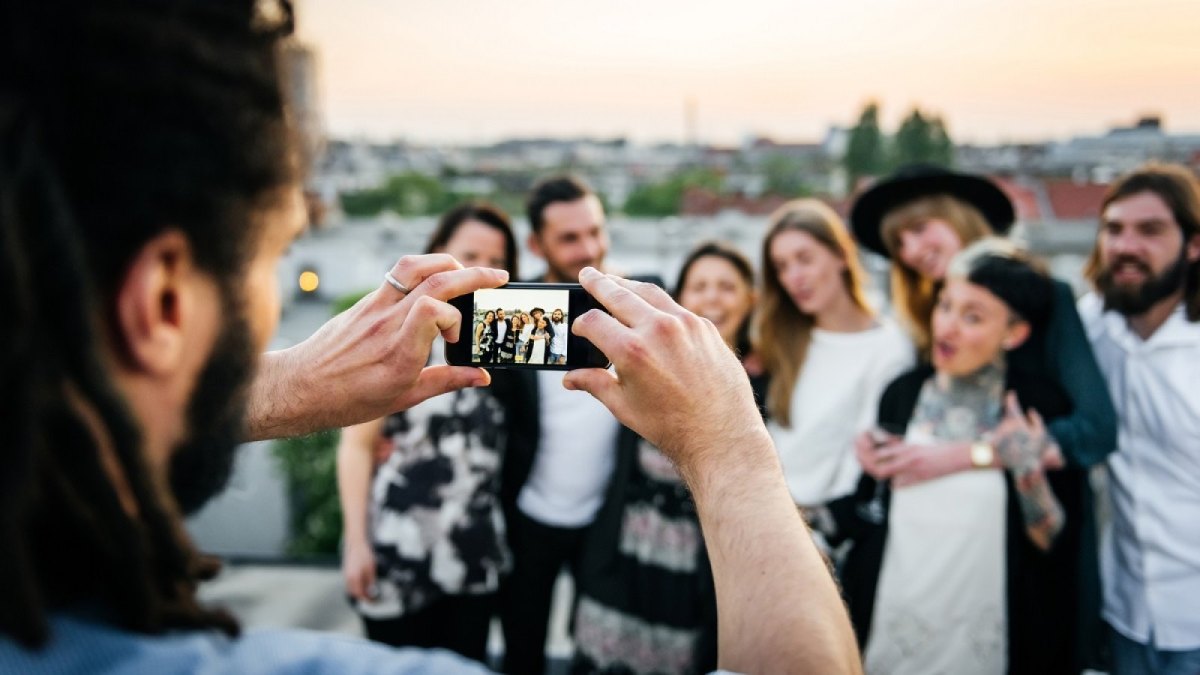 Mann fotografiert mehrere Menschen.