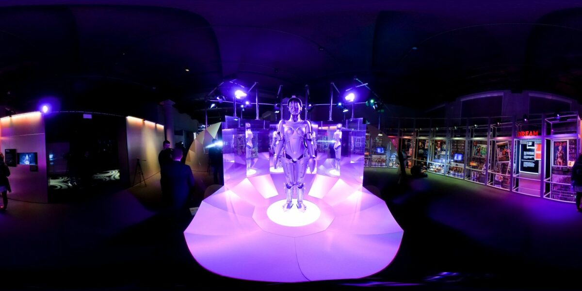 Mensch-Maschine in lilafarbenes Licht getaucht auf einer Ausstellung.