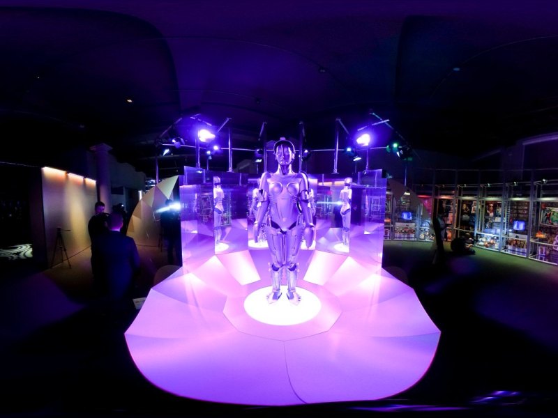 Mensch-Maschine in lilafarbenes Licht getaucht auf einer Ausstellung.