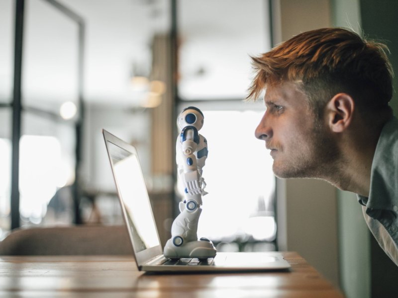 Mann starrt auf Roboter am Rechner