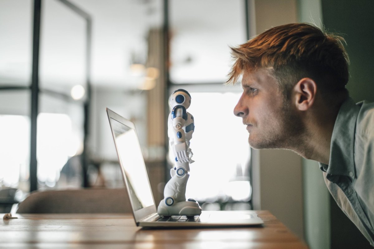 Mann starrt auf Roboter am Rechner