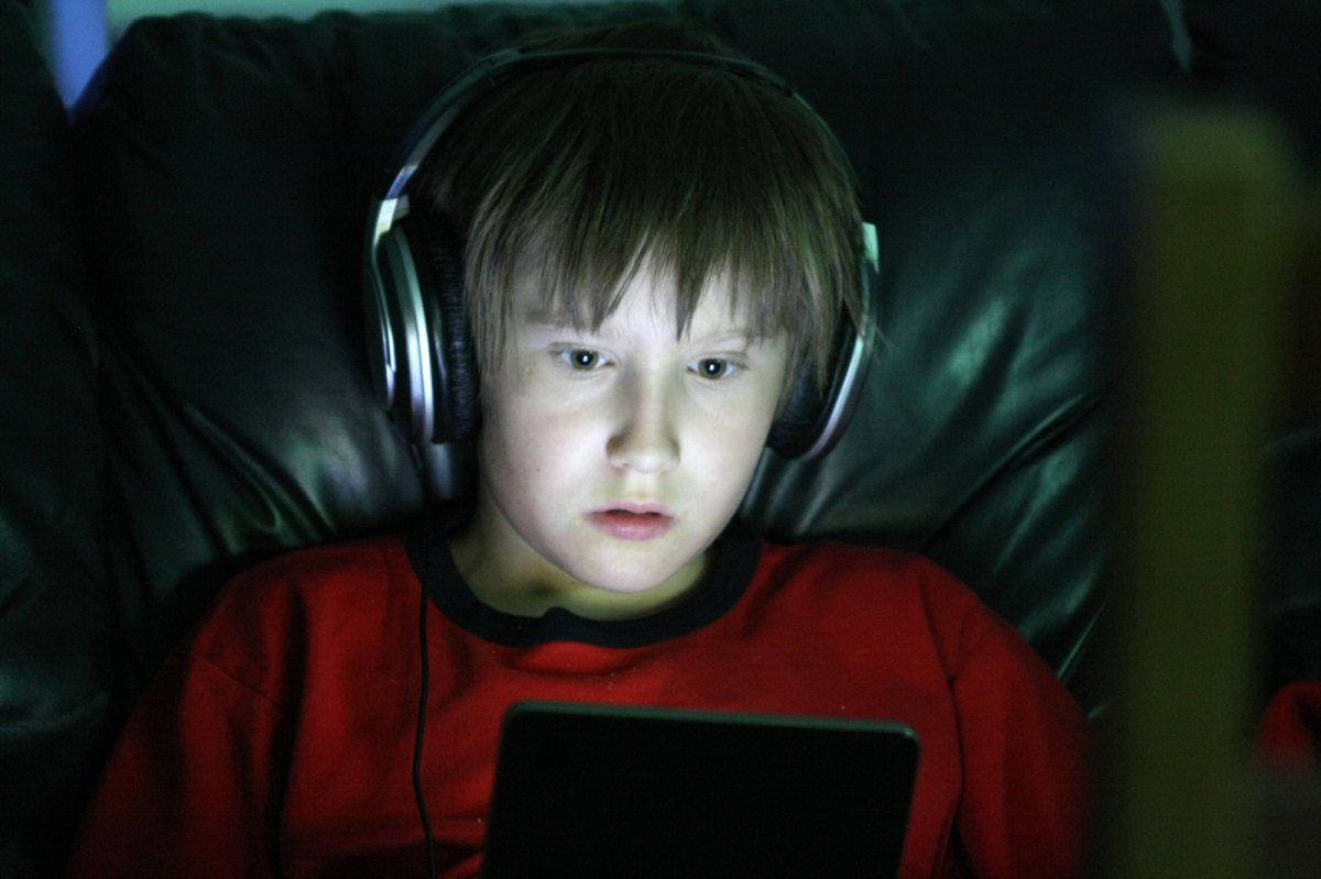 Junge sitzt vor Tablet mit Kopfhörern
