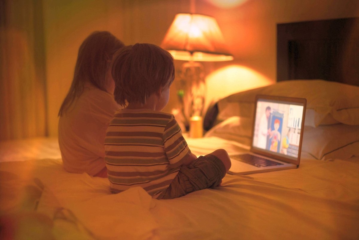 Mädchen und Junge sitzen vor einem Laptop und schauen einen zeichentrick.