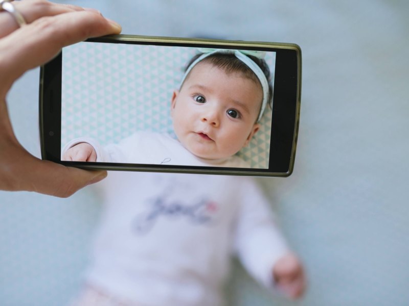 Ein Baby wird mit einem Smartphone fotografiert.