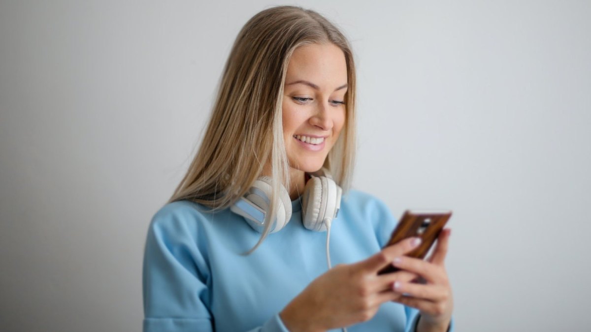 Eine Frau lächelt und schaut auf ihr Smartphone.