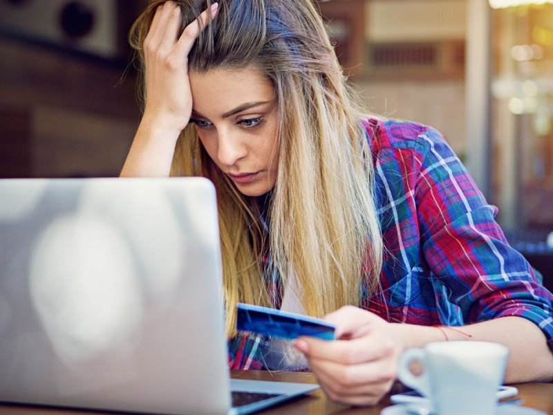 Frau mit Kreditkarte verzweifelt vor dem Laptop.