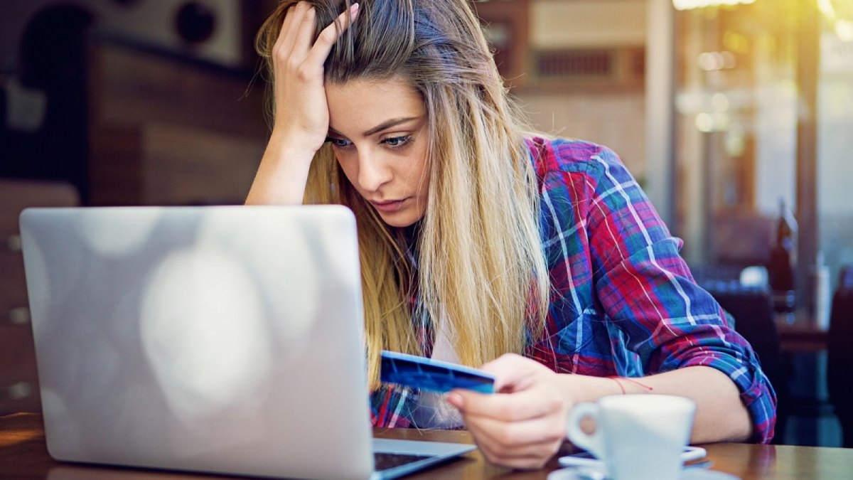 Frau mit Kreditkarte verzweifelt vor dem Laptop.
