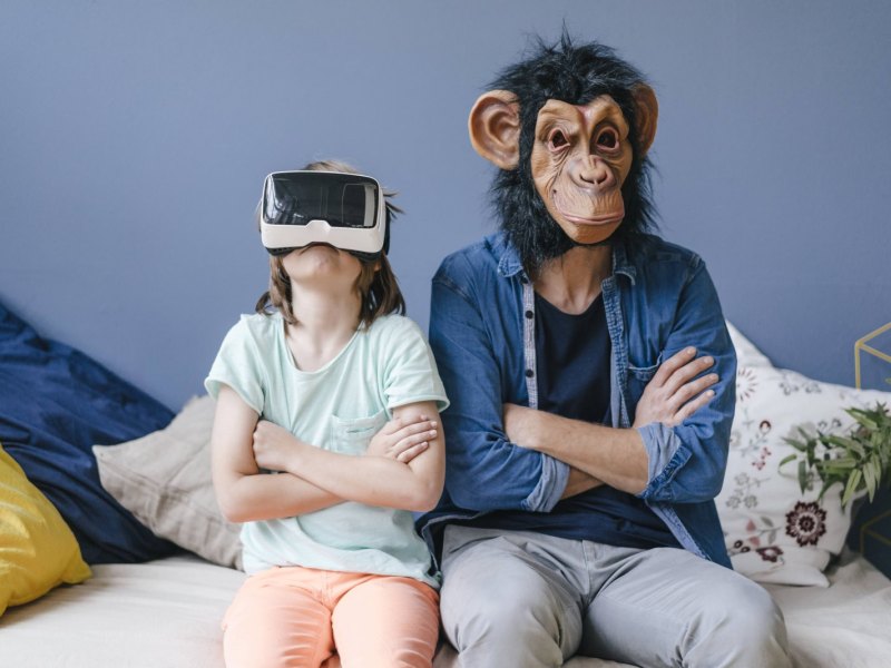 Mann mit Affenmaske neben Kind mit VR-Brille