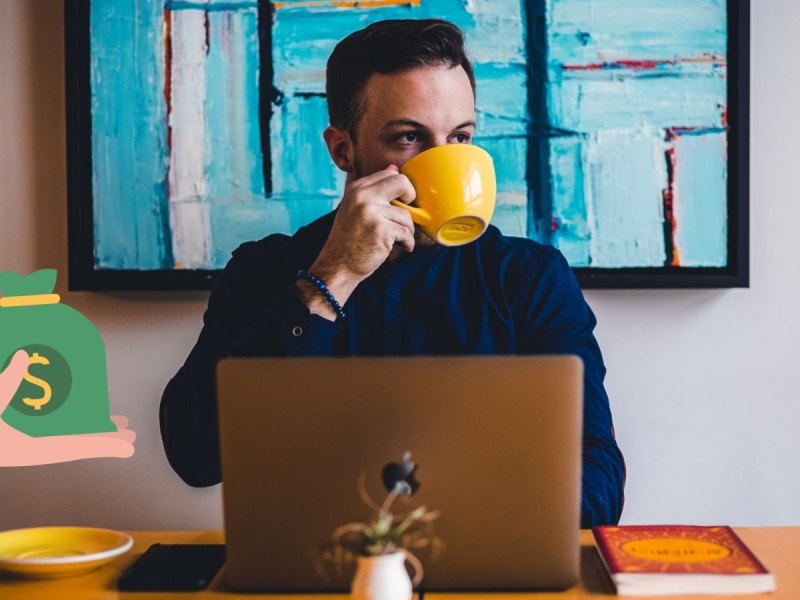 Ein Mann trinkt aus einer gelben Tasse und sitzt vor seinem Laptop.