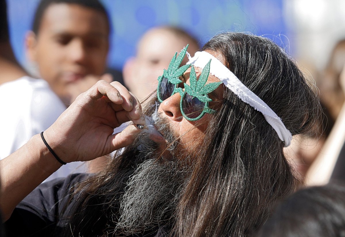 Mann mit Brille in Form von Haschisch-Blättern raucht einen Joint.