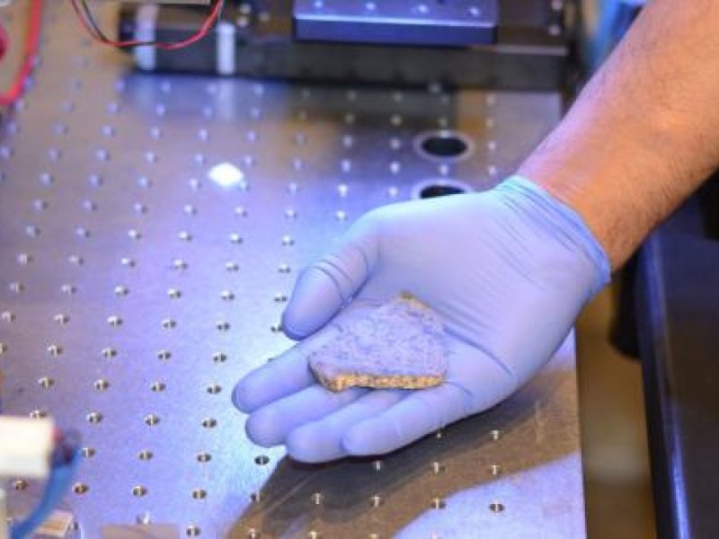 Ein Mitarbeiter der Mission Mars 2020 hält einen Teil eines Meteoriten in der Hand