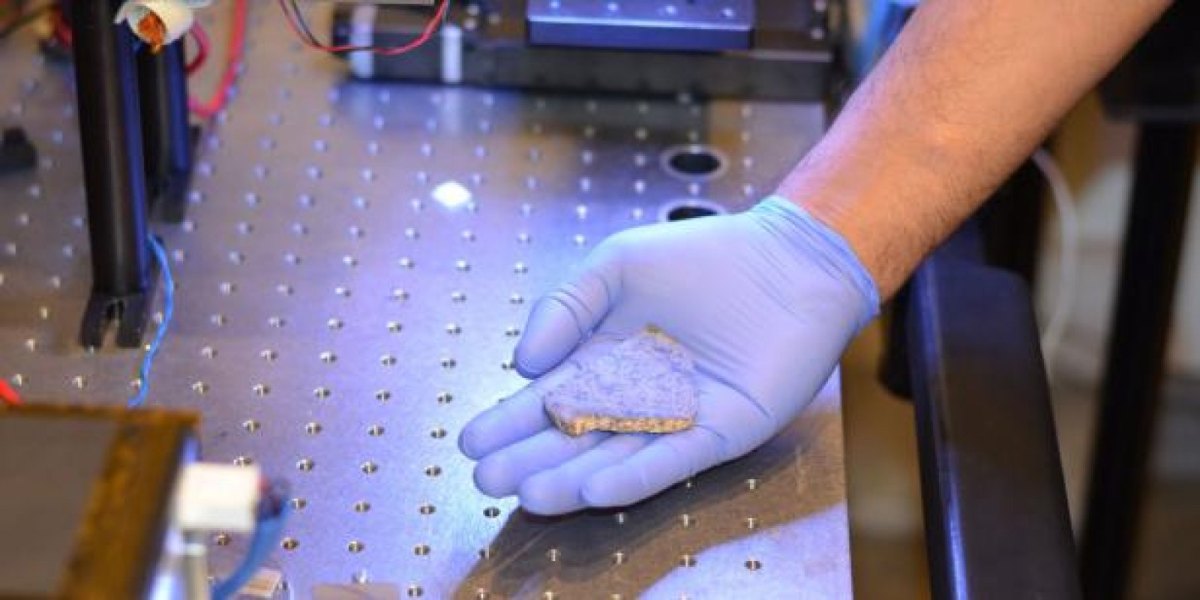 Ein Mitarbeiter der Mission Mars 2020 hält einen Teil eines Meteoriten in der Hand