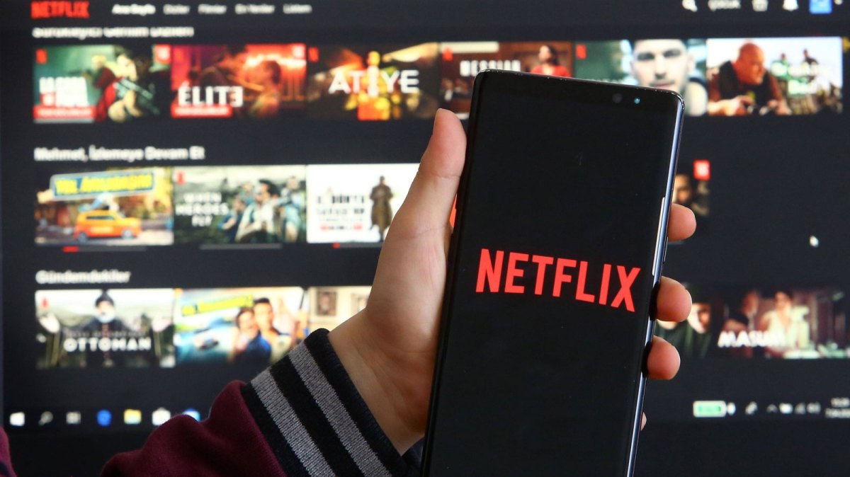 Ein Handy mit dem Netflix-Logo vor einem Fernseher mit Netflix-Oberfläche.