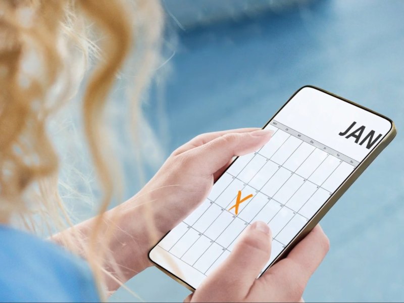 Frau hält Smartphone mit Kalender und X darauf
