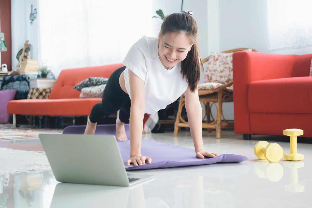 Frau macht Sport Zuhause vor dem Laptop