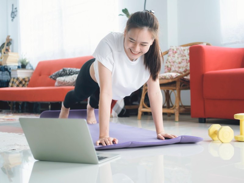 Frau macht Sport Zuhause vor dem Laptop