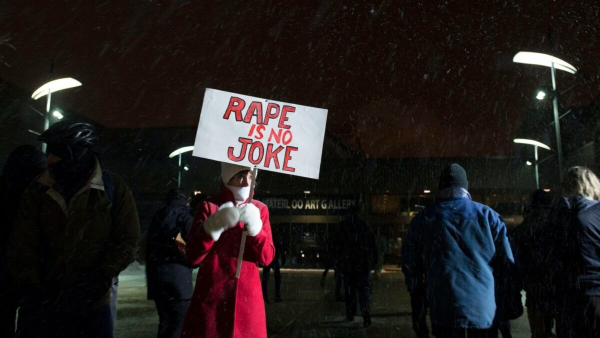 Frau protestiert mit Plakat "Rape is no Joke" gegen sexuelle Gewalt