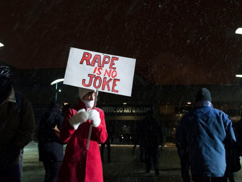 Frau protestiert mit Plakat "Rape is no Joke" gegen sexuelle Gewalt