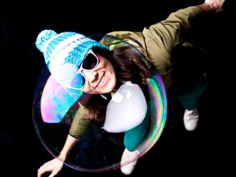 Frau mit Sonnenbrille schaut auf Riesenseifenblase.
