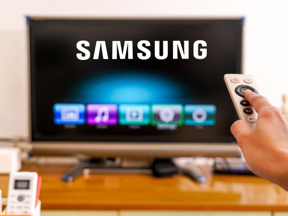 Eine Fernbedienung zeigt auf einen Fernseher mit Samsung-Logo.