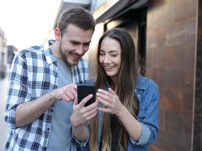 Mann und Frau schauen auf ein Handy.