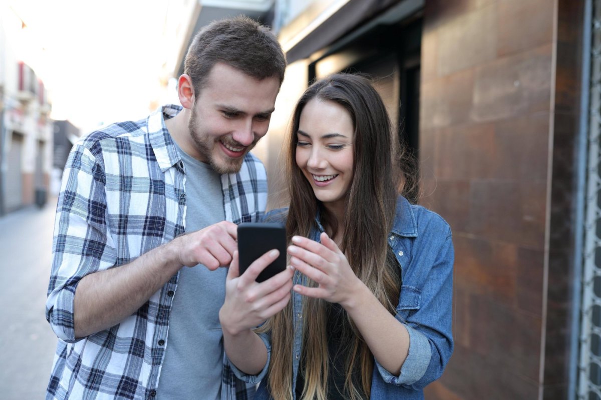Mann und Frau schauen auf ein Handy.