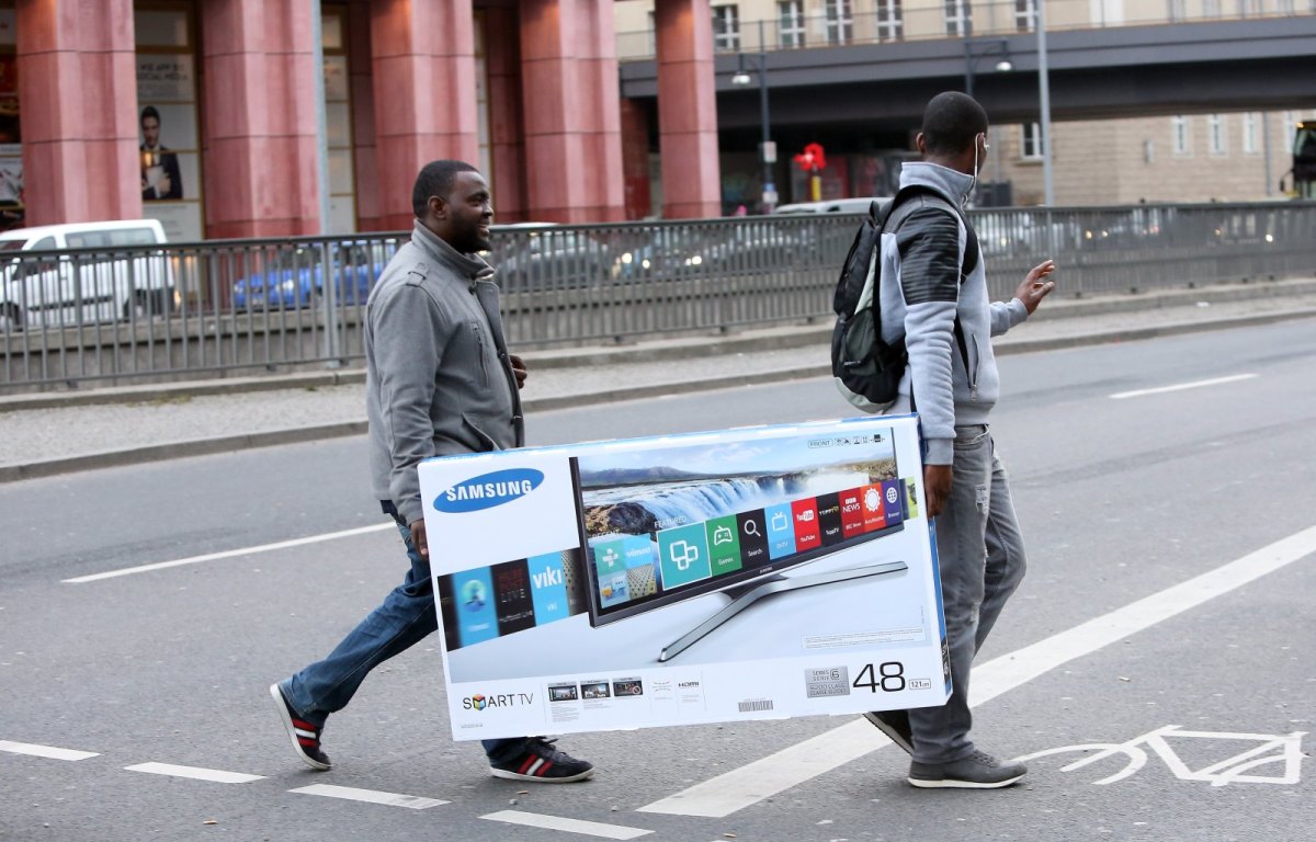 Männer tragen gekauften Samsung-Fernseher über die Straße