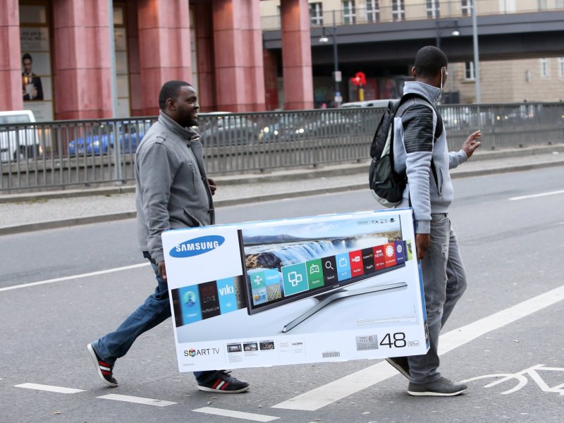 Männer tragen gekauften Samsung-Fernseher über die Straße
