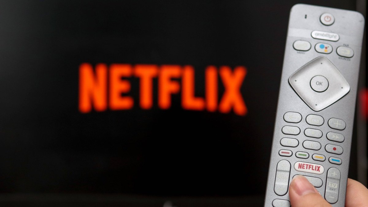 Fernbedienung mit Netflix-Logo vor einem Netflix-Bildschirm.