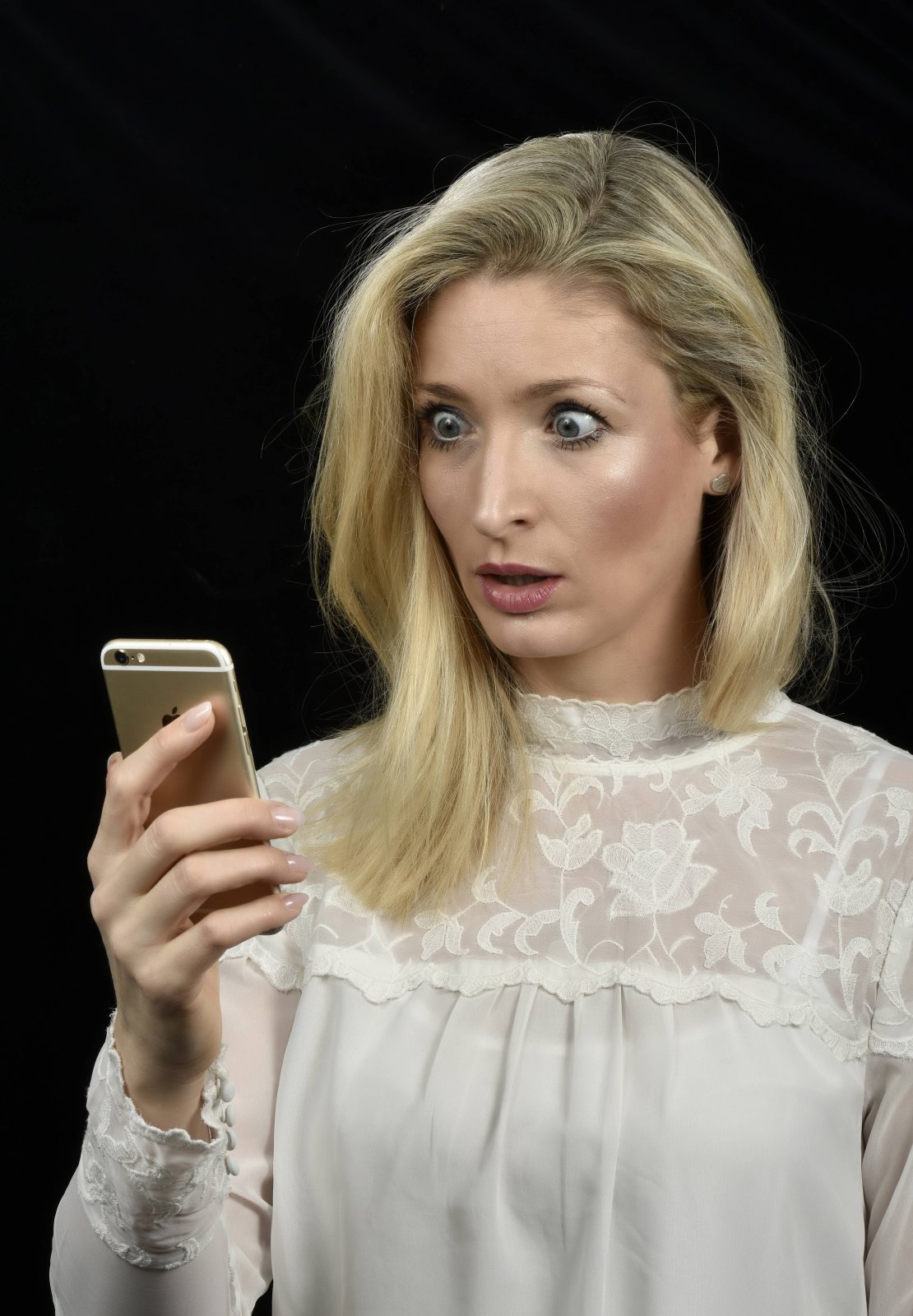 Eine Frau schaut entsetzt auf ihr iPhone.
