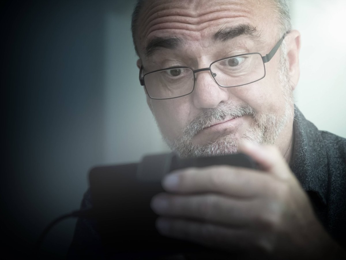 Rentner schaut skeptisch auf ein Smartphone