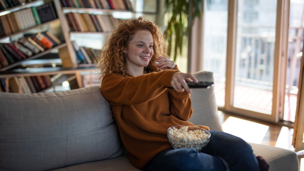 Frau mit Popcorn vor dem TV.